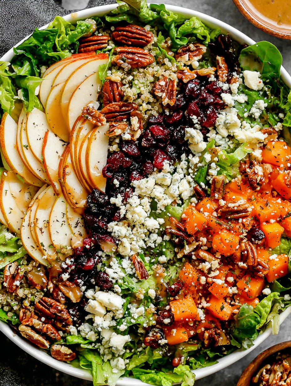 A bowl of salad with apples, oranges, and pecans.