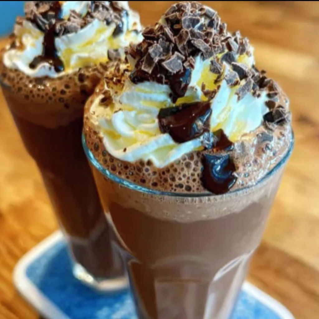 Two chocolate milkshakes with whipped cream.