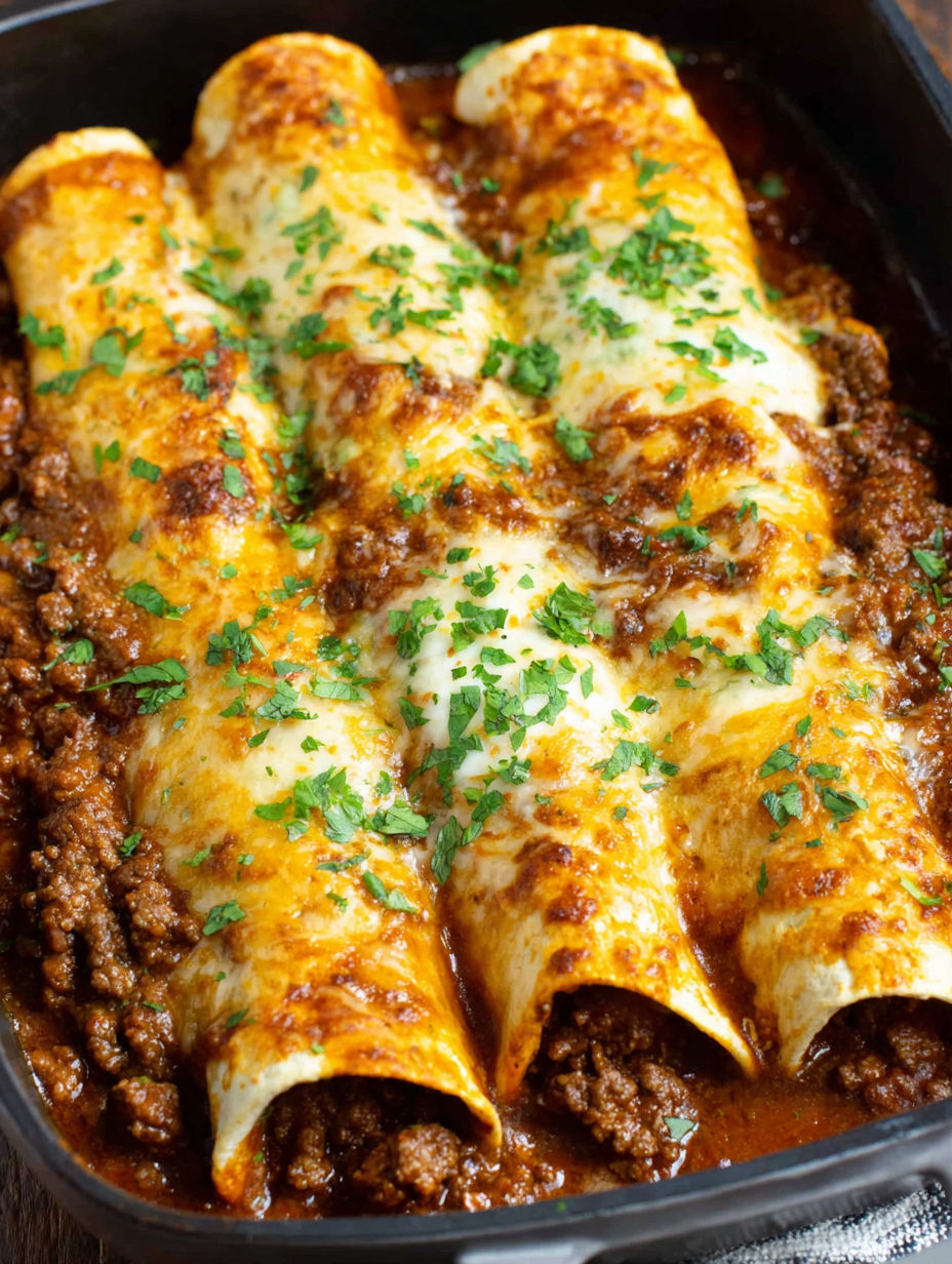 A dish of beef enchiladas with red sauce.