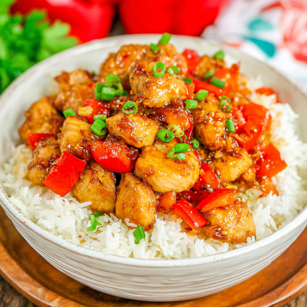 A bowl of rice with chicken and peppers.