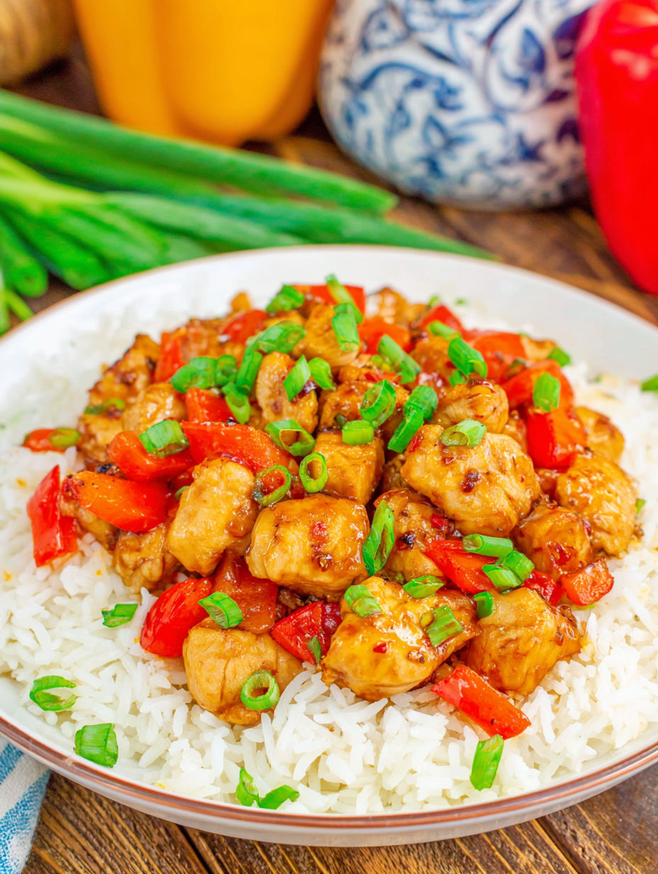 A plate of rice and chicken with peppers on top.