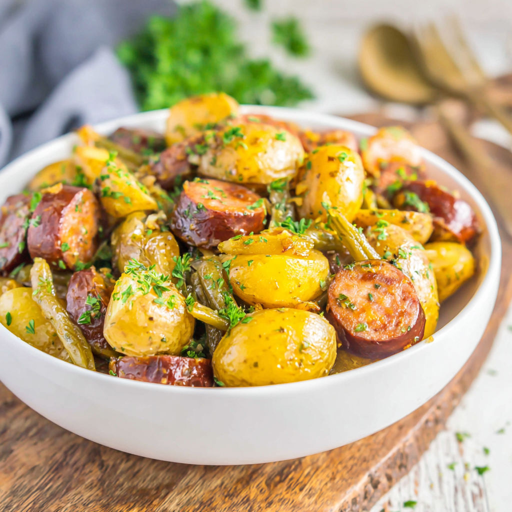A white bowl filled with potatoes and sausage.