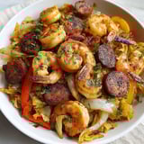 A bowl of shrimp, sausage, and cabbage.