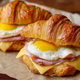 Two croissants with eggs and ham.