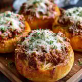 Three garlic bread bowls filled with spaghetti.