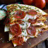 A pepperoni pizza quesadilla fusion is stacked on a wooden board.