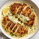 A plate of Parmesan crusted chicken with lemon.