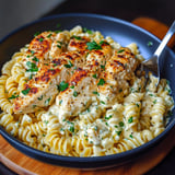 A plate of pasta with chicken and garlic sauce.