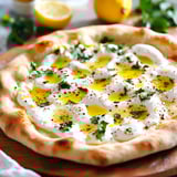 A pizza with white cheese and yellow lemon slices on top.