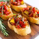 A plate of toasted bread with tomatoes and basil.