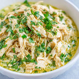 A bowl of shredded chicken with green herbs.