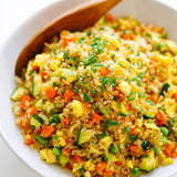A bowl of rice with vegetables and a wooden spoon.