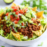 A bowl of taco salad with lettuce, tomatoes, and avocado.