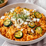 A bowl of rice with zucchini and feta cheese.