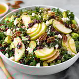 A bowl of salad with apples, pears, and honey dressing.