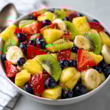A bowl of fruit salad with bananas, kiwi, strawberries, and blueberries.