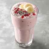 A glass of pink smoothie with bananas and red berries.