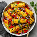 A bowl of grilled corn salad with cilantro and peppers.