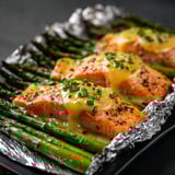 Two pieces of salmon with sauce and asparagus.