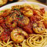A plate of spaghetti with garlic, tomatoes, and shrimp.