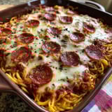 A baked spaghetti pizza dish with pepperoni and cheese.