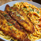 A bowl of spaghetti with fish on top.