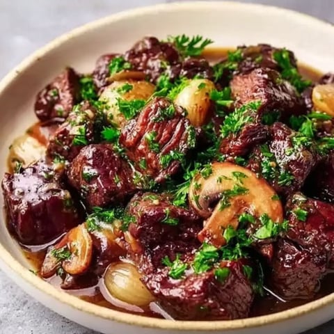 A bowl of beef stew with mushrooms and onions.