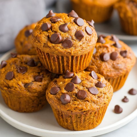 A plate of muffins with chocolate chips on top.