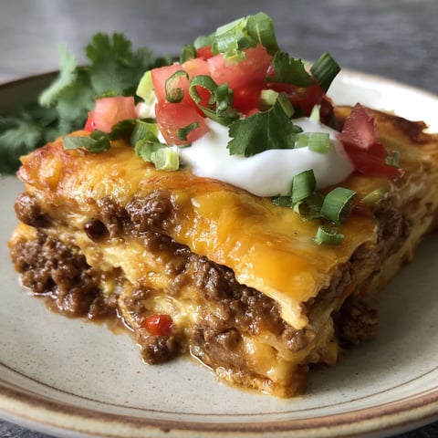 A plate of food with a cheesy taco lasagna dinner.